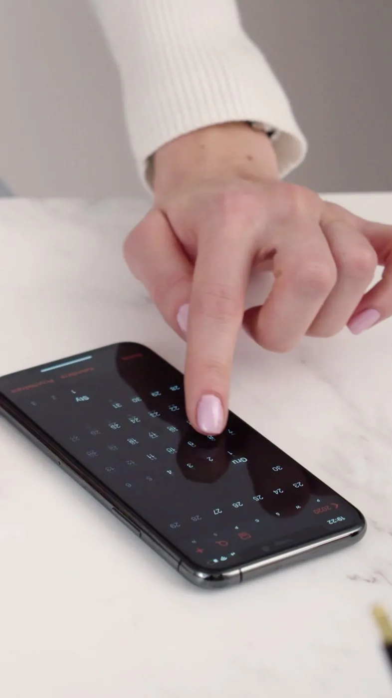 Hands check a phone calendar against a paper planner.