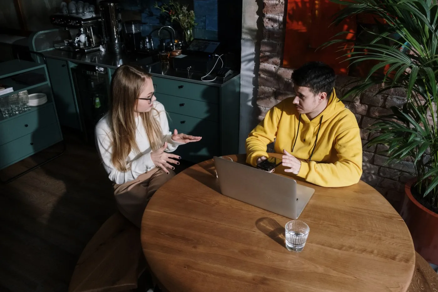 Two people in conversation across a wooden table.