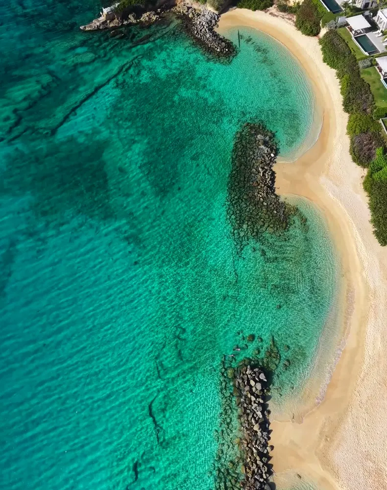 Aerial view of a turquoise bay and white sand, a beach retreat destination.