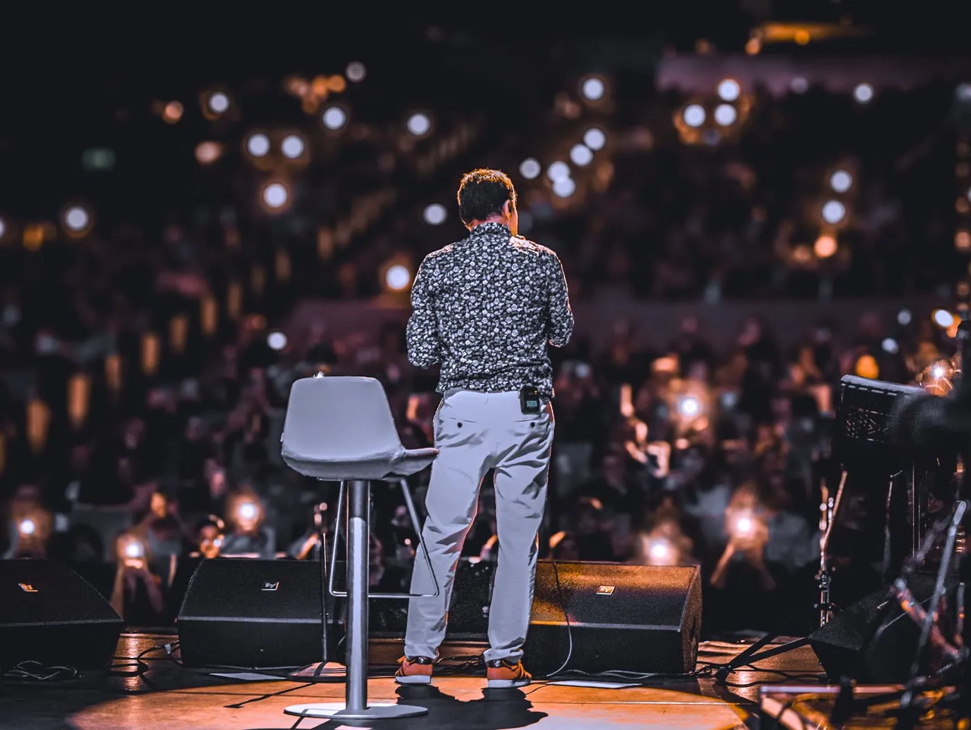 A guest speaker on stage at a member retreat, the audience holding up phone lights.