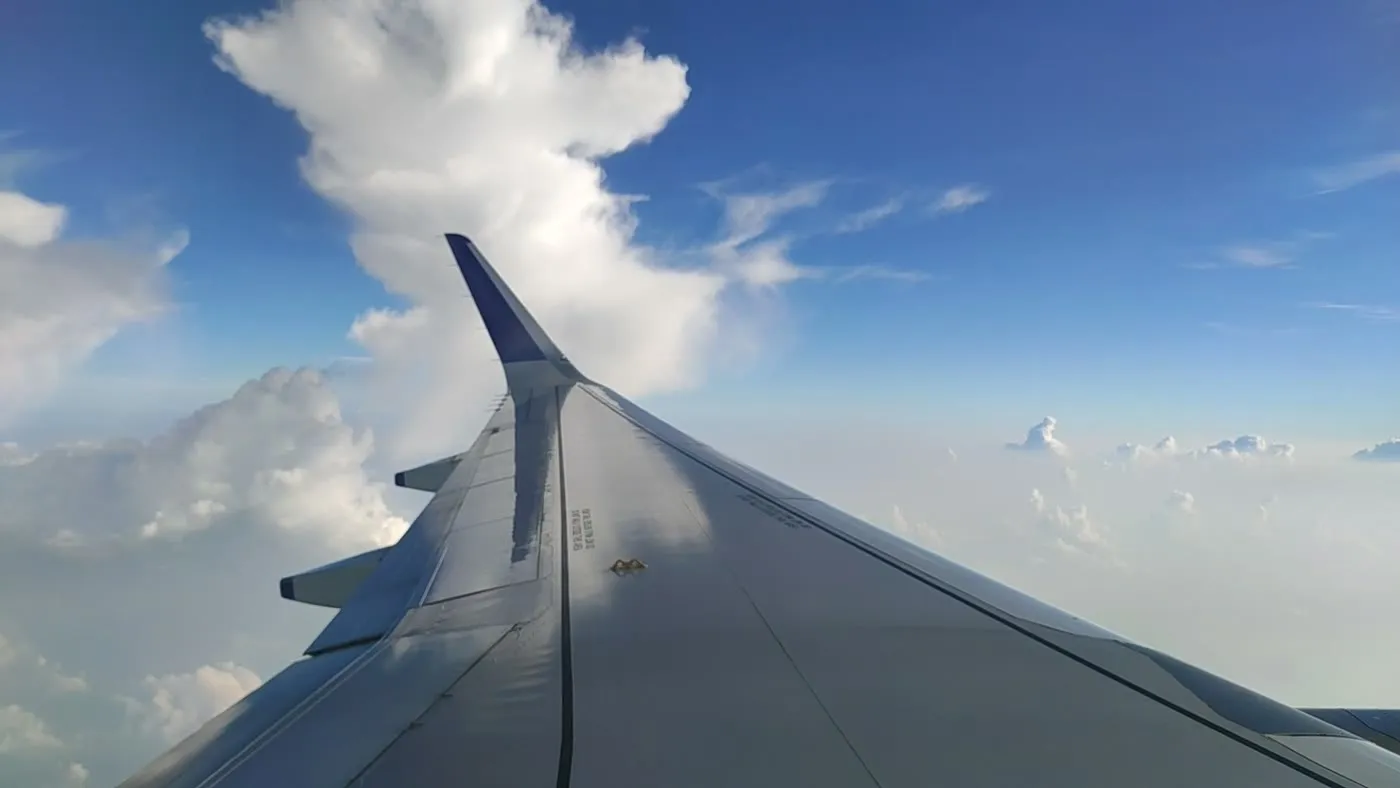 An airplane wing beside a tower of cumulus cloud on the flight out.
