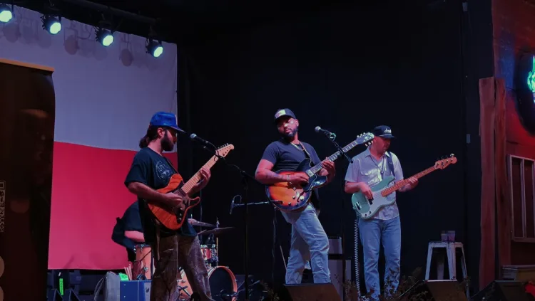 A band on stage in front of a Texas flag backdrop.