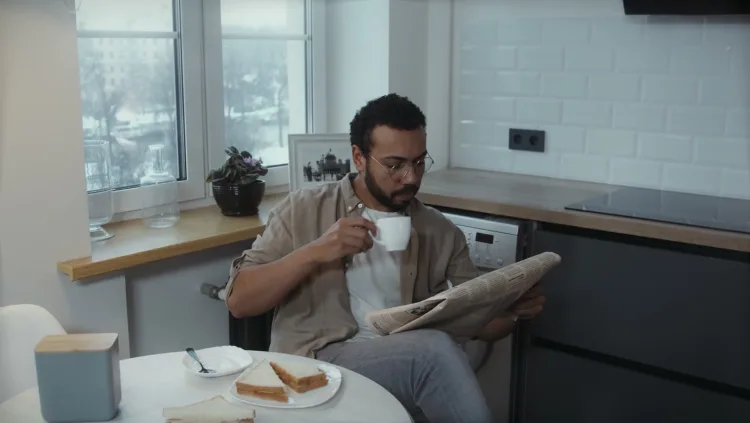 A man reads the morning paper over coffee at a kitchen table.